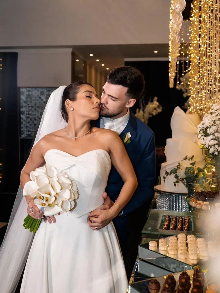 Noivos se beijando ao lado do bolo