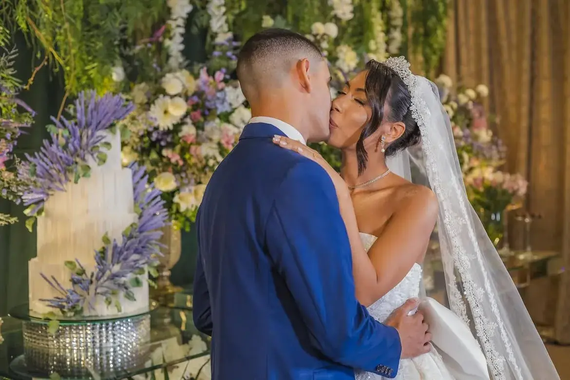 Beijo dos noivos sob o arco de flores